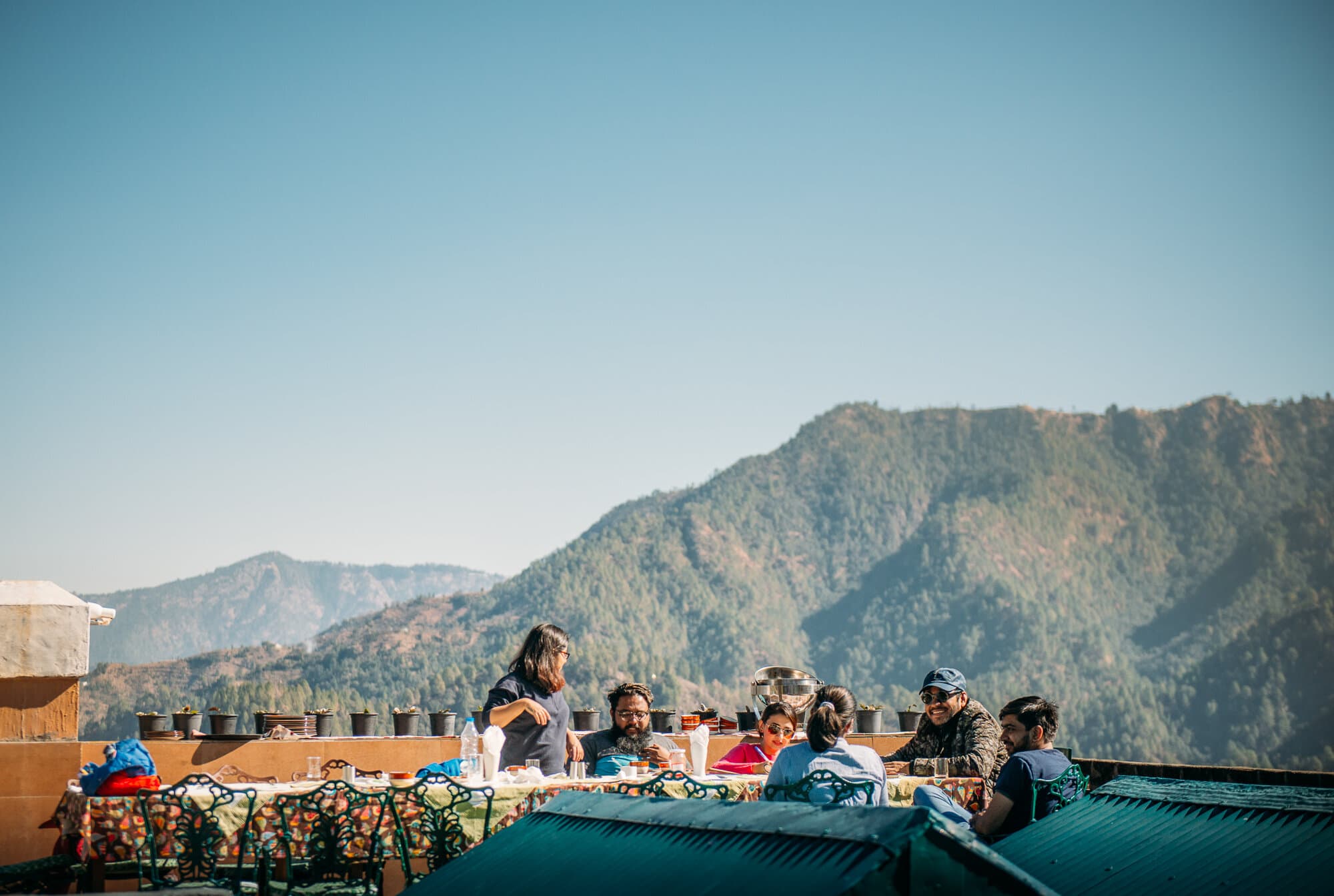 People sharing a meal with mountains behind them at BHX Nainital.