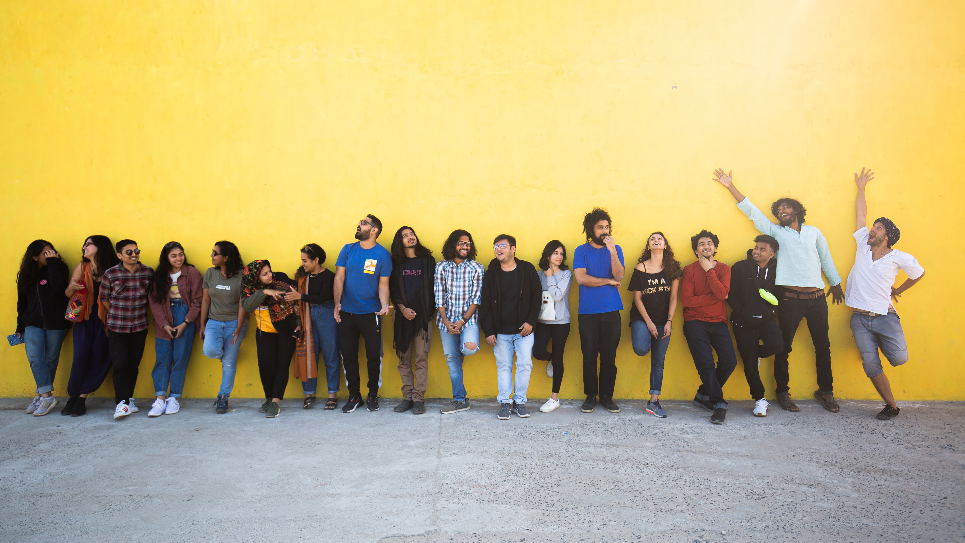 A group of travellers standing together against a yellow wall.